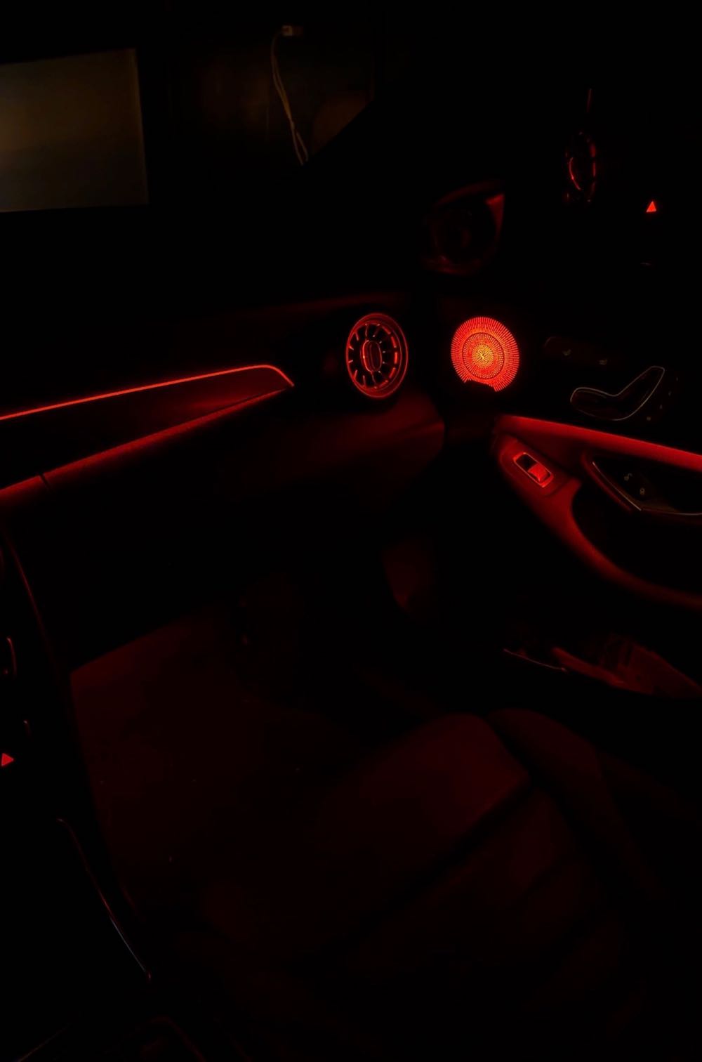 Red ambient lighting glowing through the vents and speaker grille of a Mercedes